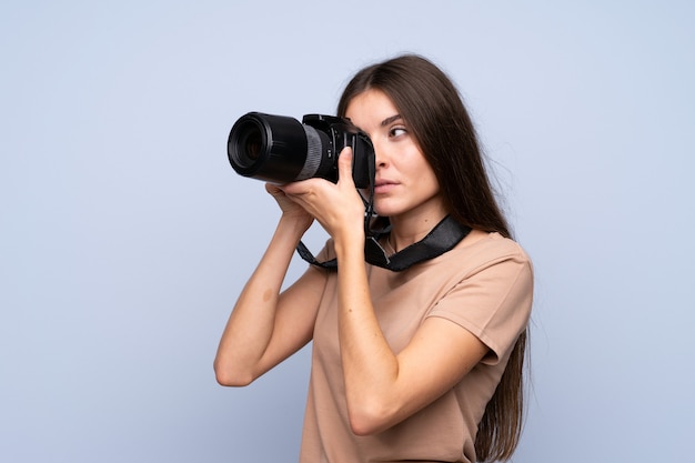 Young woman over isolated  with a professional camera