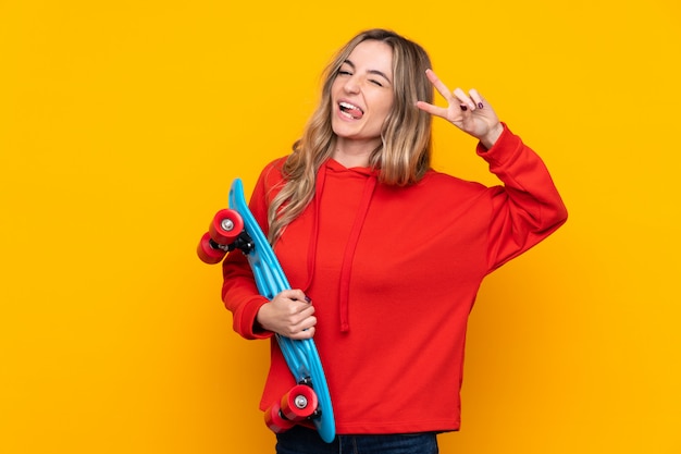 Young woman over isolated yellow wall with a skate with happy expression