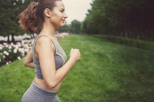 Young woman jogging down a path in a green park