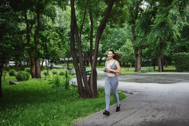 Young woman jogging down a path in a green park