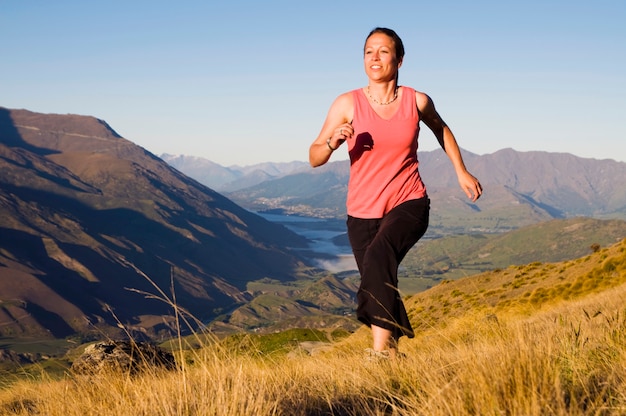 Young woman jogging in the wilderness with mountain range as a background.