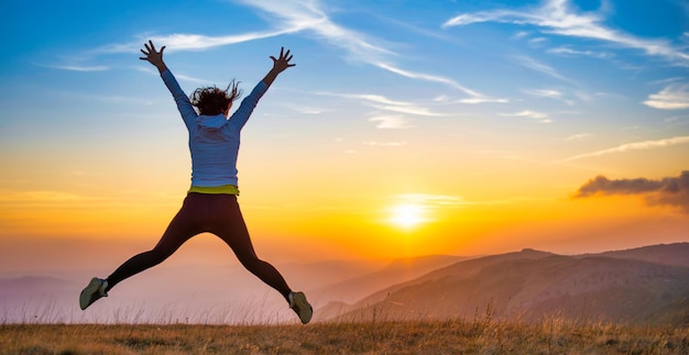 Young woman jumping at sunset mountains