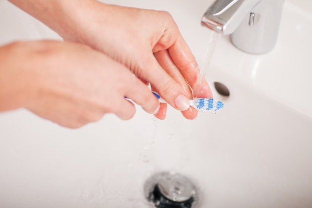 Young woman (just hands) cleaning her teethbrush