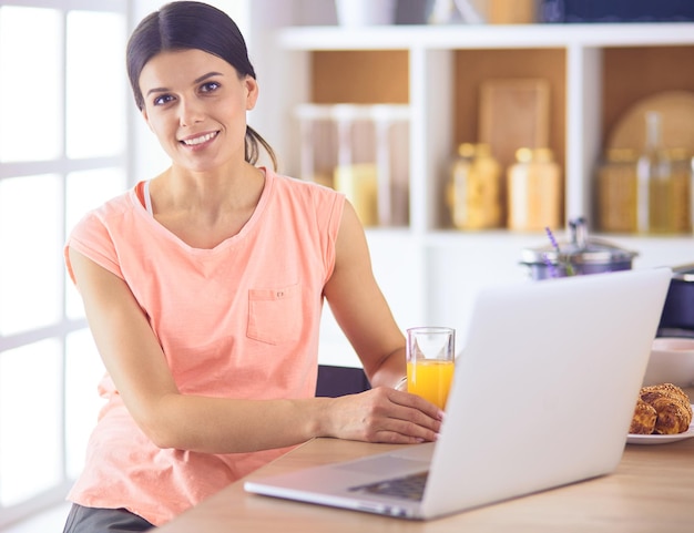 Young woman in kitchen with laptop computer looking recipes smiling Food blogger concept