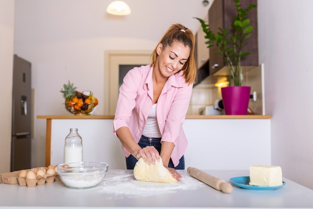 Young woman knead dough at kitchen