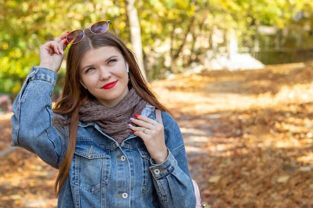 Young woman listen to music in an autumn park