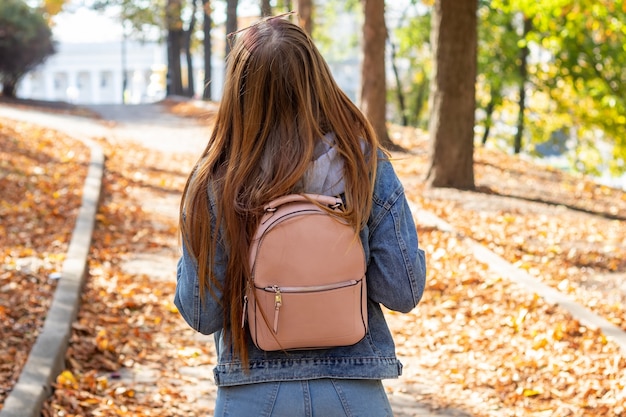 Young woman listen to music in an autumn park