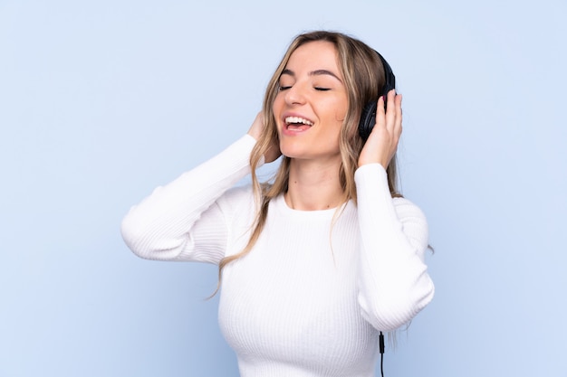 Young woman listening music over isolated wall