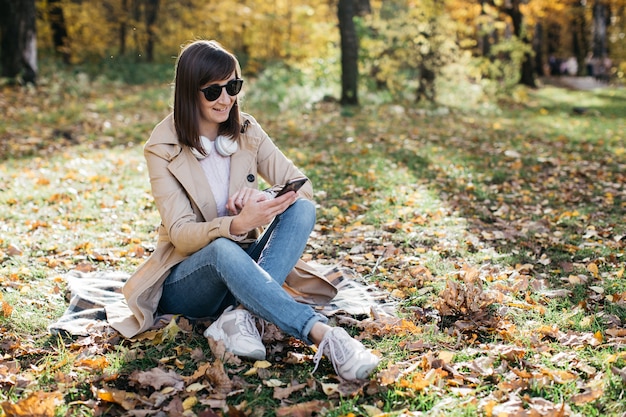 Young woman listening to music with headphones in the autumn forest