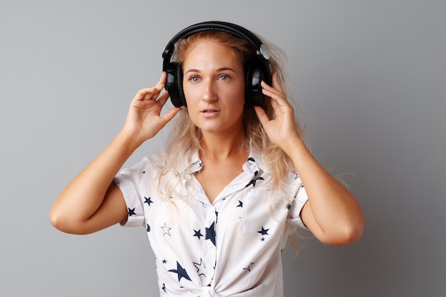 Young woman  listening to music with her headphones over a grey  