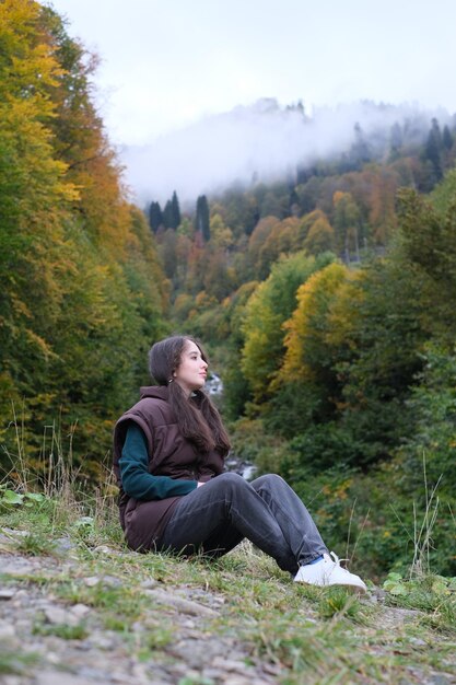 Young woman looking away while sitting on land