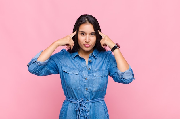 Young woman looking concentrated and thinking hard on an idea, imagining a solution to a challenge or problem