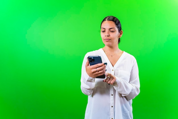 Young woman looking at her phone green background