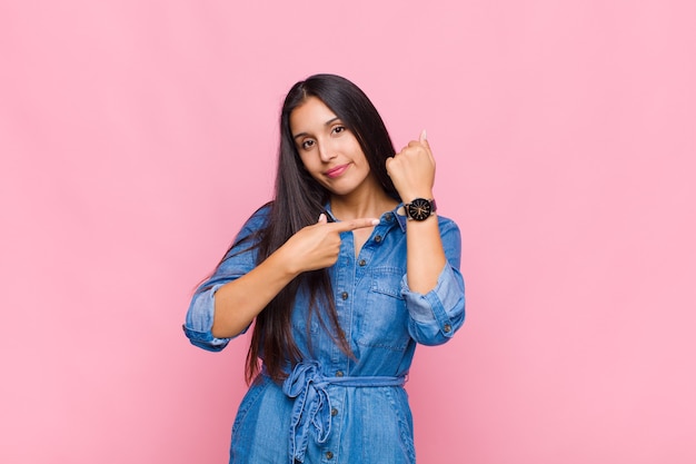 Young woman looking impatient and angry, pointing at watch