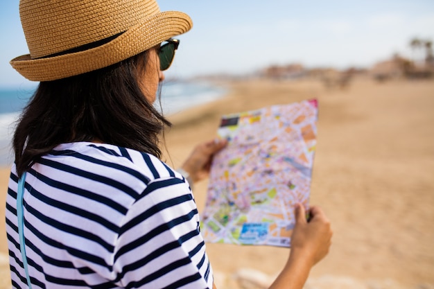 Young woman looking at the map in front of the sea