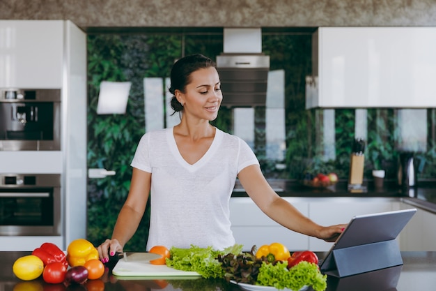 The young woman looking at recipe in laptop in kitchen