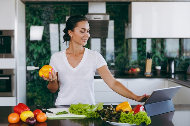 The young woman looking at recipe in laptop in kitchen