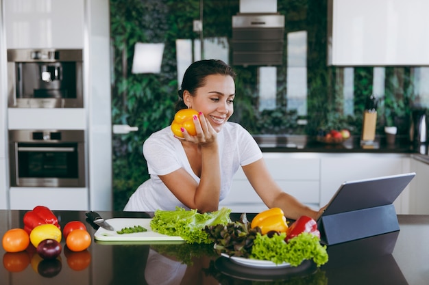 The young woman looking at recipe in laptop in kitchen