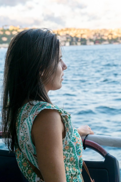 Young woman looking at the scenery from a cruise ship on a Bosphorus tour in Istanbul Turkey