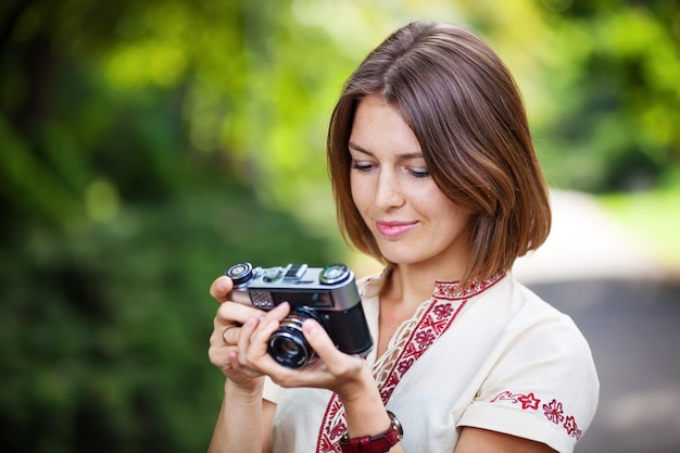 Young woman looking at screen of retro style camera and smiling