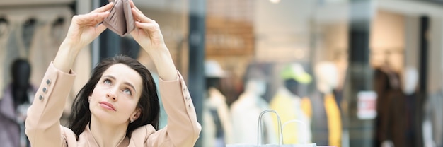 Young woman looks into empty wallet in mall