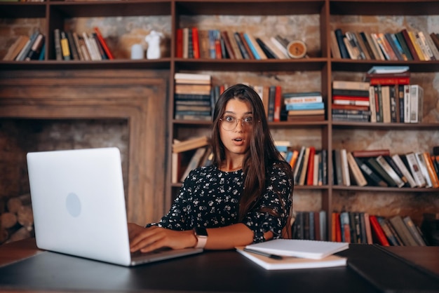 Young woman looks shocked after reading while works at the laptop