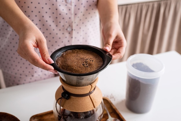 Young woman in lovely pajamas making coffee at home kitchen