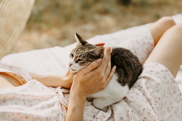 Young woman lying on a bed, outdoors, in the backyard and playing with a kitten