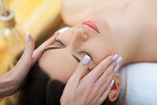 Young woman lying on a massage table,relaxing with eyes closed. Woman. Spa salon