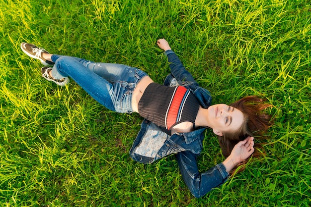 Photo young woman lying in nature on green grass in park relaxing smiling her red