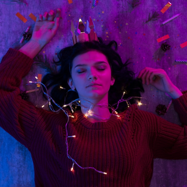 Young woman lying with Christmas glowing lights celebration.