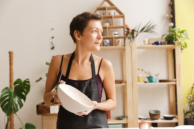 Young woman making ceramic and pottery tableware at the workshop