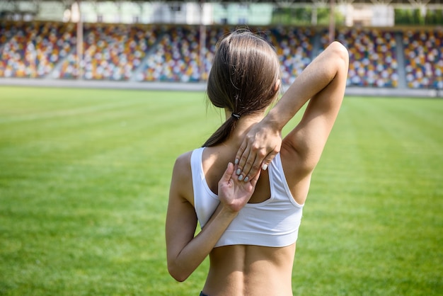 Young woman making exercises with hands over her back