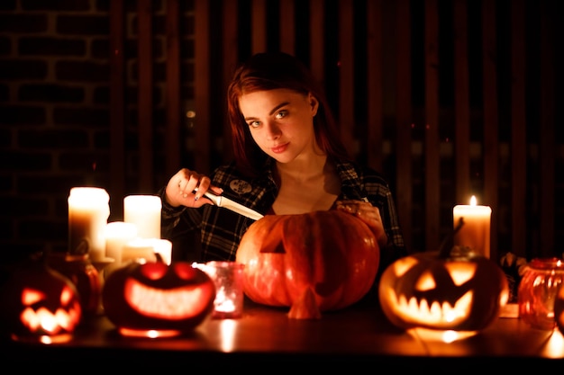 Young woman making halloween pumpkin jackolantern female hands cutting pumpkins with knife