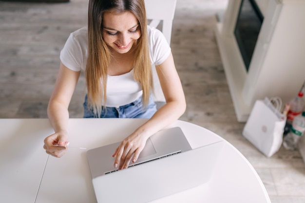 Young woman making online payment for purchases using credit card and laptop