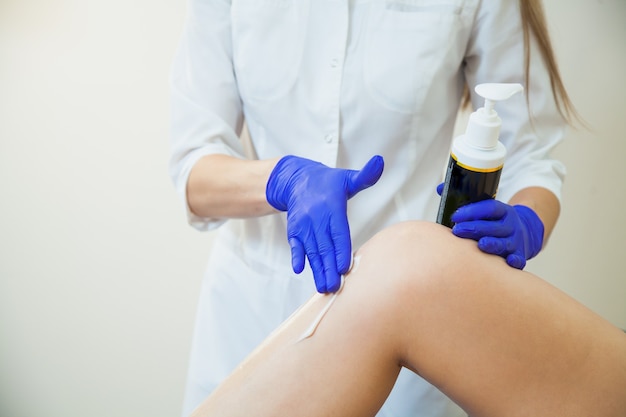 Young woman making sugaring hair removal procedure at beauty salon