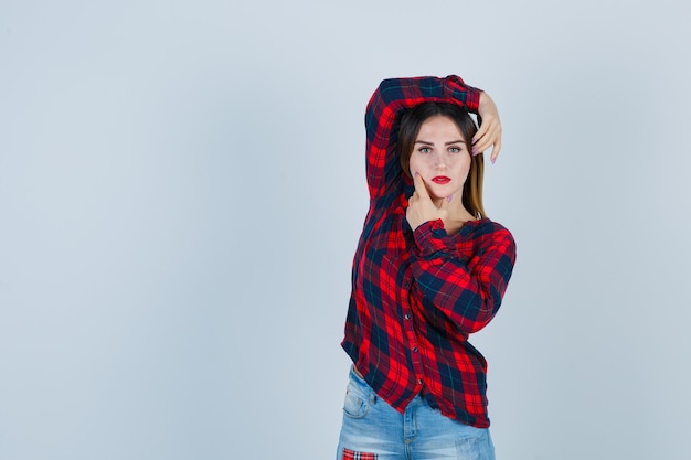 Young woman making vogue pose in checked shirt and looking alluring , front view.