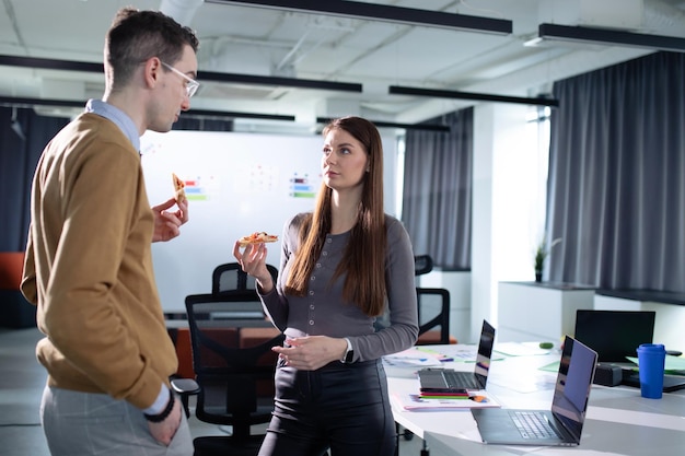 A young woman and a man communicate during lunch in the office