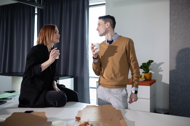 A young woman and a man communicate during lunch in the office