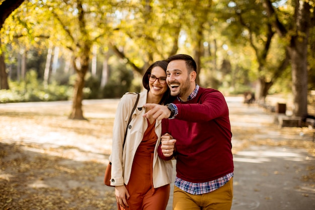 Young woman and man walking in city park holding hands