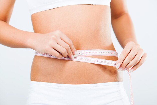 Young woman measuring perfect shape of waist