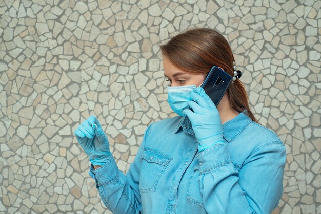 Young woman in medical mask looking at thermometer