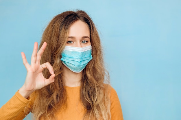 Young woman in a medical mask showing OK. Coronavirus epidemic. Covid 2019.