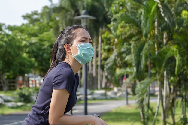 The young woman in medical protective mask relaxing in the park.  campaign to use protective mask from COVID19