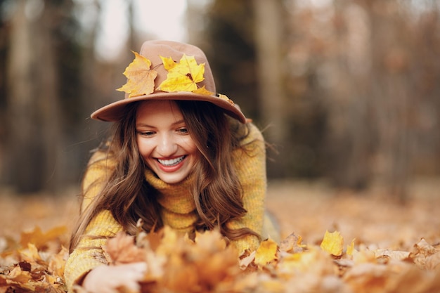 Young woman model in autumn park with yellow foliage maple leaves Fall season fashion