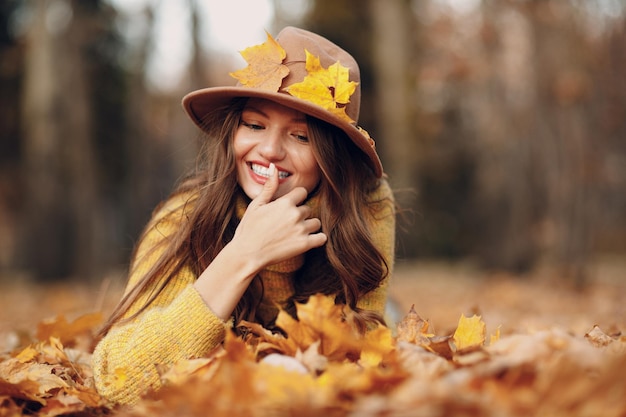 Young woman model in autumn park with yellow foliage maple leaves Fall season fashion