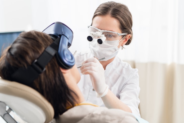 A young woman on a modern dental treatment, using VR glasses to distract her from the unpleasant dental procedures.