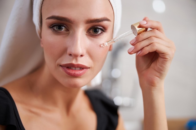 Young woman moisturizing her face with a special product