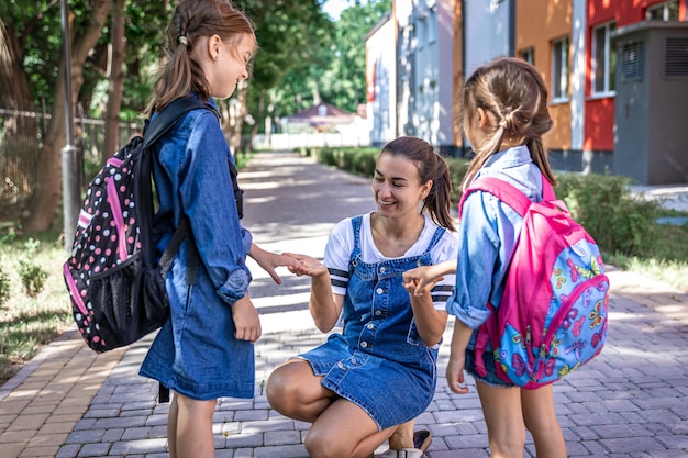 A young woman morally supports the daughters holding hands encourages the children, accompanies students to school.