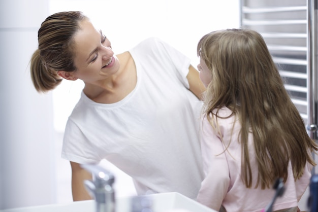 Young woman mother looking at baby and smiling in bathroom portrait